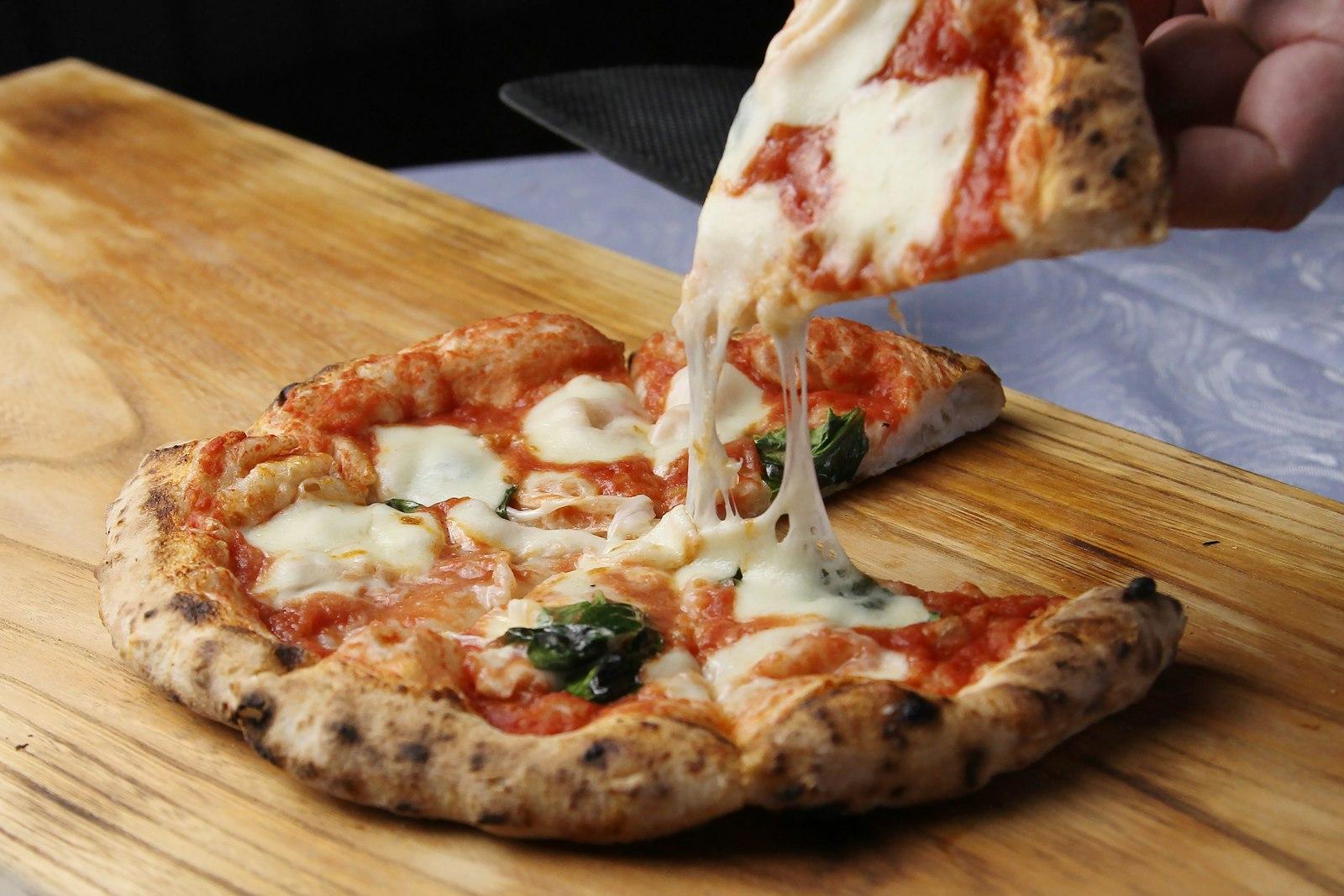 A Person Taking A Slice Of Pizza From A Wooden Cut jigsaw puzzle preview