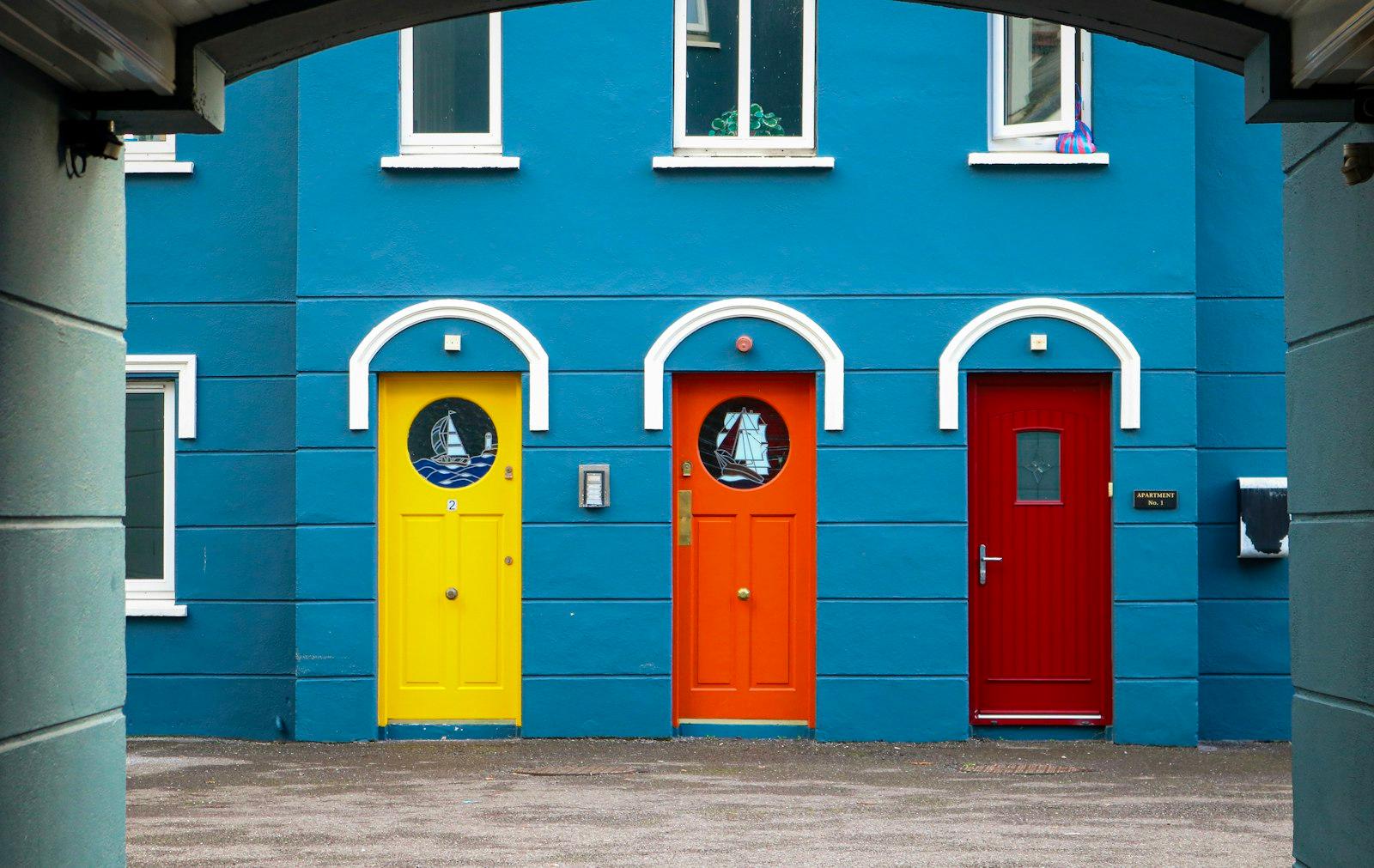 A Row Of Brightly Colored Doors In Front Of A Blue jigsaw puzzle preview
