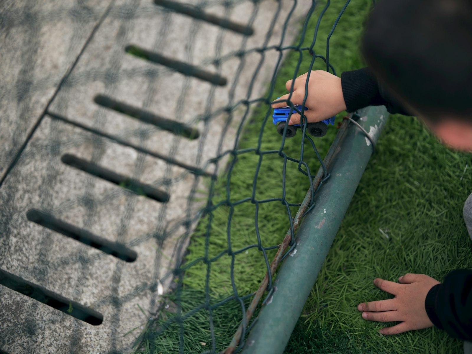 Child'S Hand Holding A Blue Toy Car Near A Net jigsaw puzzle preview