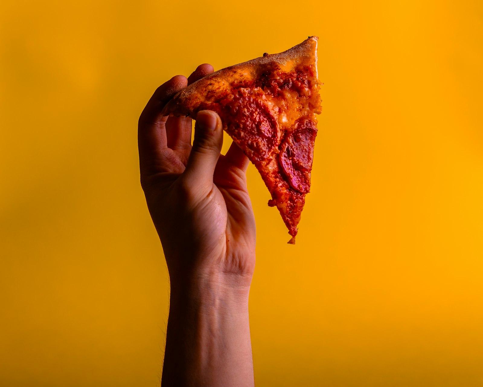 Hand Holding Slice Of Pizza On Yellow Background jigsaw puzzle preview