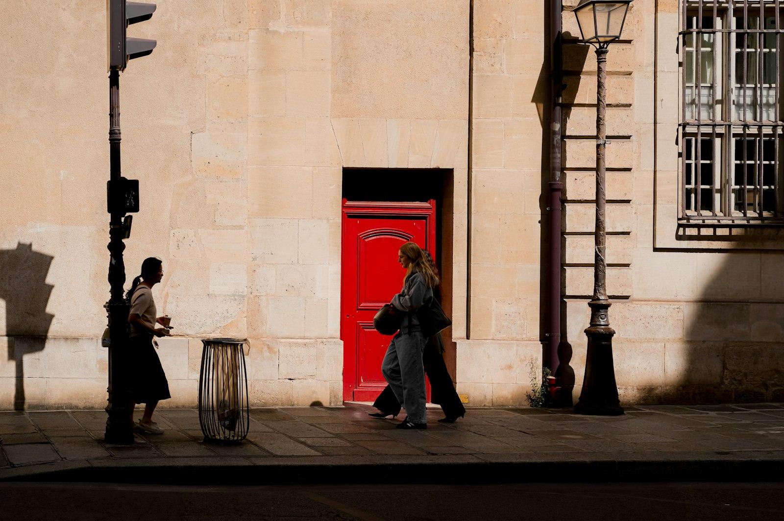 People Walk Past A Red Door In The Sun jigsaw puzzle preview