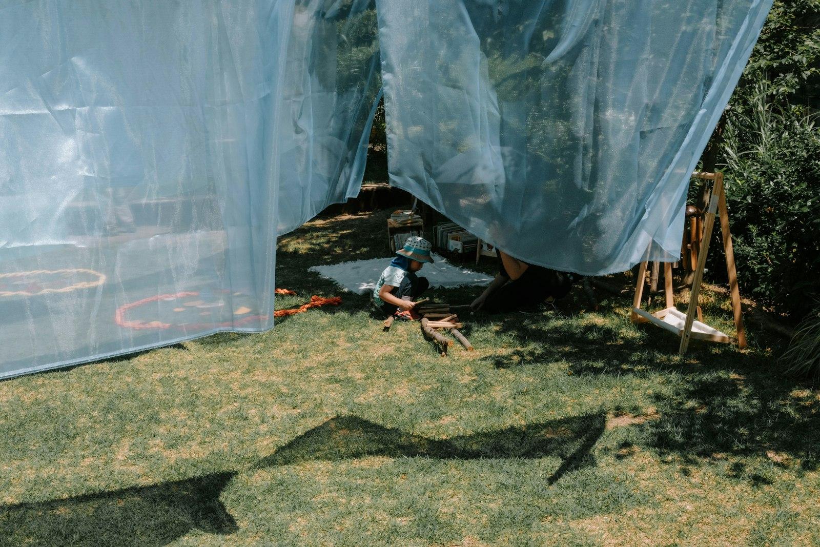 Person Sitting Under Blue Netting In A Grassy Yard jigsaw puzzle preview